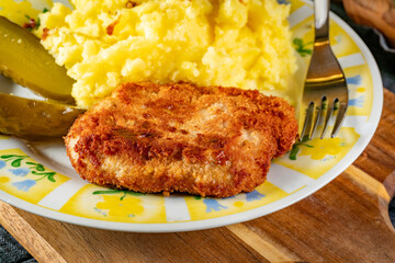 Minced meat cutlet served with mashed potatoes and pickled cucumber.