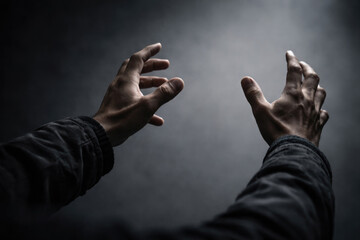 A man's hands reaching for the light in the dark.