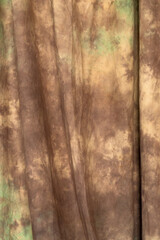 Abstract brown and olive tie-dye fabric texture with soft drapery folds. Professional mottled textile backdrop for portrait photography