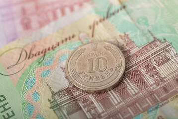 Ukrainian 10 hryvnia coin on banknote background. Close-up of national currency, finance, and economy concept. Selective focus on cash. Savings, budgeting, spending, inflation