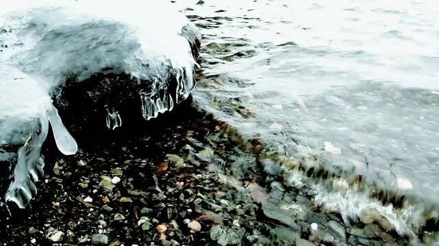 The winter shore of a reservoir at dawn, where the water's edge meets the icy patches...
