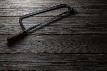 Old Bow Hand Saw on Dark Weathered Wood Background Top View
