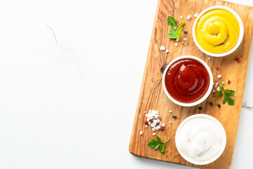 Ketchup, mayonnaise and mustard in the bowls on white background.