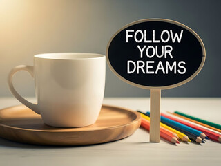 White coffee mug on wooden tray with follow your dreams sign and colored pencils
