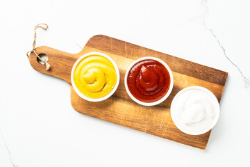 Ketchup, mayonnaise and mustard in the bowls on white background.