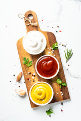 Ketchup, mayonnaise and mustard in the bowls on white background.