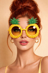 A young woman is wearing sunglasses with a frame shaped like a pineapple fruit