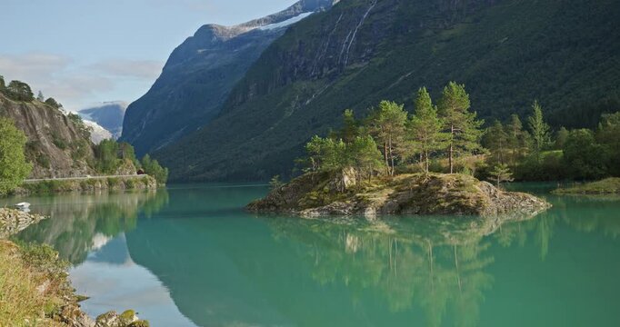 Pine islet on turquoise Lovatnet, Loen, Norway - reflections, waterfalls and distant glacier