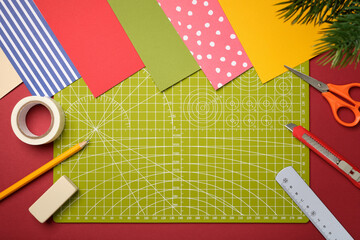 Items for paper crafts. Green cutting mat, pencil, scissors, eraser, knife, ruler, tape. Space for your text.