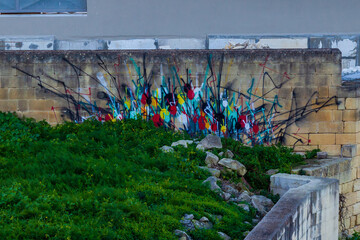Colorful Graffiti Wall Behind Green Hill and Stone Terrace in Urban City Setting