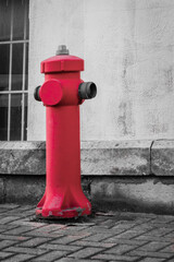 Red Fire Hydrant Stands Boldly On City Sidewalk Against Gray Wall, Creating Striking Urban Contrast