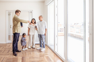 Fototapeta premium Real estate agent giving house keys to family at unfurnished apartment