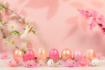 Beautiful Easter banner with decorated festive eggs, sakura and cherry blossom branches, rabbits and feathers. Happy Easter concept. An abstract spring Easter composition with space for text