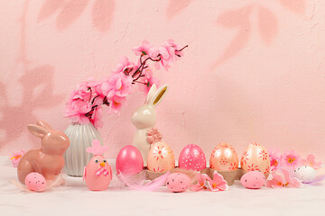 Beautiful Easter banner with decorated festive eggs, sakura and cherry blossom branches, rabbits and feathers. Happy Easter concept. An abstract spring Easter composition with space for text