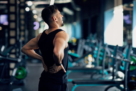 Portrait Of Young Arab Bodybuilder Suffering Lower Back Pain At Gym, Upset Middle Eastern Male Athlete Rubbing Painful Sore Zone After Getting Sport Injury, Having Lumbar Spine Ache, Copy Space