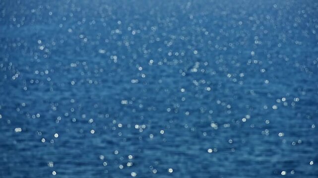 Soft focus ocean sparkles. Glowing highlights dance on water. Blurry sea reflects sunlight. Ocean bokeh feels dreamy. Gentle glow spreads across waves. Sea shimmer looks abstract.