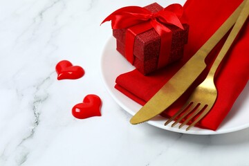 Close-up view photo with plate, cutlery, gift box, red hearts on marble background with empty...