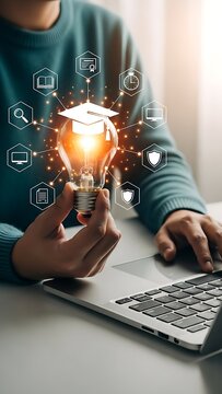 Person holding glowing lightbulb with education icons on laptop