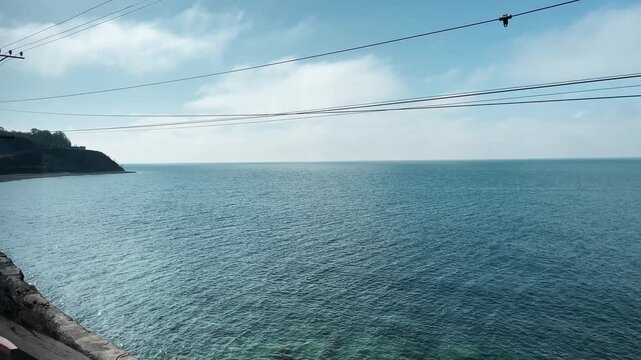 View of the Black Sea coastline in spring seen from a moving train along the Tuapse to Sochi railway. Concept of travel, slow journey, coastal nature, and peaceful seaside landscape
