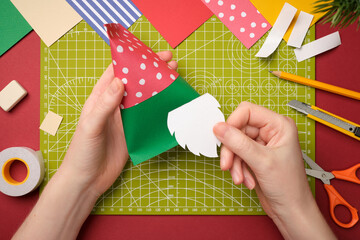 Making a craft. Hands glue a paper beard to the gnome's body. Creative process.