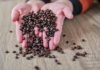 top-Down View of Hands Releasing Roasted Coffee Beans onto a Wooden Table