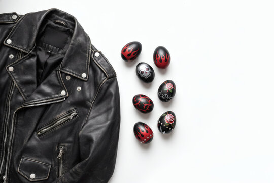 Black leather biker jacket with decorated Easter eggs beside it, alternative Easter banner with copy space on a white background - Powered by Adobe