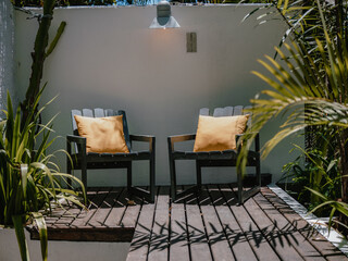 Two armchairs with yellow cushions on wooden deck, modern outdoor corner
