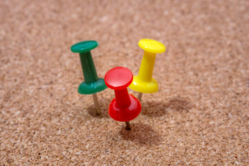 Close up of colorful push pins fixed into a cork board surface. Representing planning, organization, reminders and office concepts. Ideal for business, education, workflow and design projects.