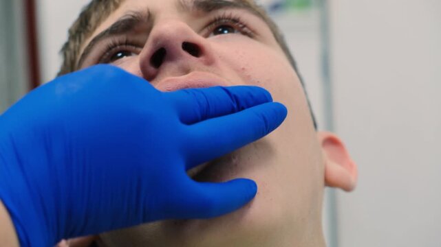 Dentist hands roughly place a temporary dental prosthesis on a patient causing pain and discomfort. Partial temporary Butterfly type denture with metal clasps. Dental prosthetics.