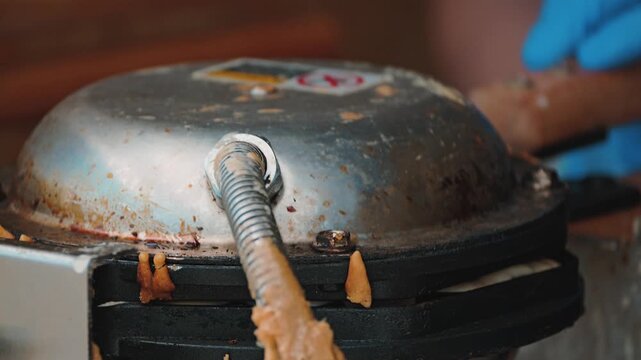 A close-up of the batter being poured onto a hot waffle iron. The mixture spreads evenly into the indentations, creating a delicious treat. The waffle iron is closed and flipped