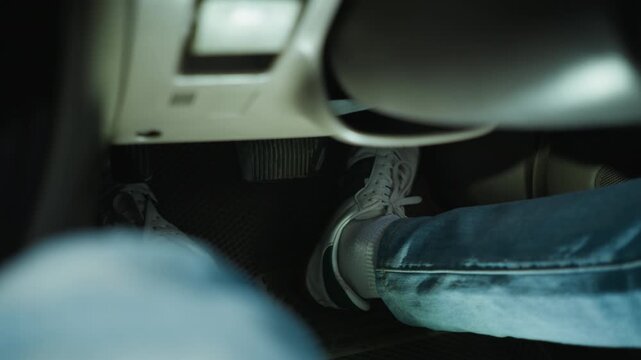 Closeup foot on pedal inside car, commuter in jeans easing off brake and pressing accelerator, casual sneaker on textured floor mat, low cabin light, dashboard blurred, urban commute tension, student