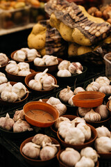 Fototapeta premium Fresh Garlic Bulbs At Market Stall: White Whole Garlic Displayed In Bowls With Natural Texture And Warm Traditional Food Market Atmosphere