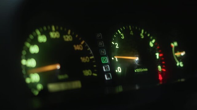 blurry illuminated speedometer and tachometer glow closeup of car instrument cluster at night with green backlight, needle movement suggesting acceleration, motion bokeh and low light atmosphere,