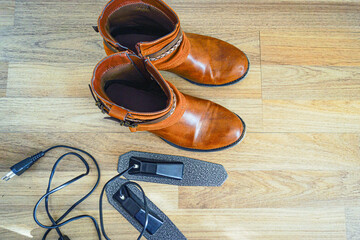 Women's eco-leather boots near unplugged electric shoe dryer. Represents fungal contamination defense, long commute recovery routine, small apartment solutions, and climate adaptation equipment.