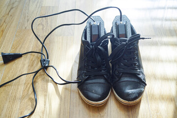 Black commuter shoes beside electric hygiene inserts for comprehensive moisture and bacterial control. Illustrates urban foot health management, climate adapted living, and cold weather survival gear.