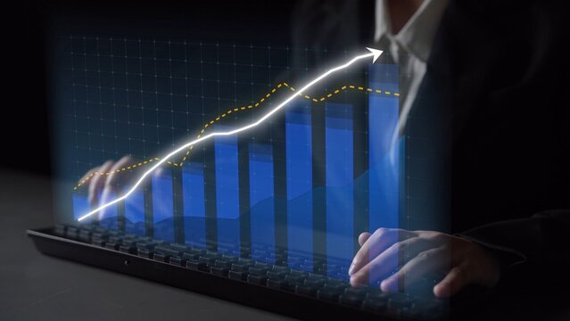 A business professional engages with a digital display of financial graphs and data analytics while using a keyboard in a modern office setting. Copula - Powered by Adobe