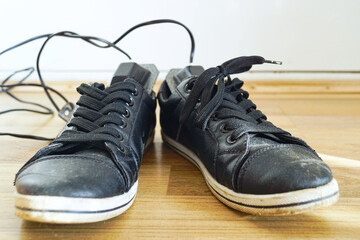 Dirty urban shoes with electric shoe dryer showing real world hygiene application. Illustrates authentic commuter foot health needs, everyday infection prevention, and cold climate adapted routines.