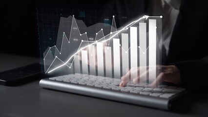 A close-up view of hands typing on a keyboard, with a virtual graph overlay illustrating business growth and data analysis, showcasing digital transformation in finance. Copula