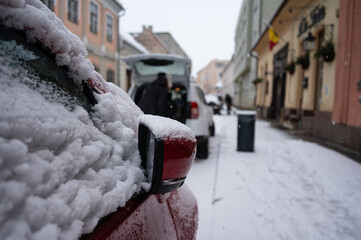 Snow covered red car detail during winter snowfall
