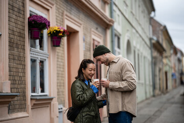 Fototapeta premium Happy multicultural couple enjoying coffee on city street