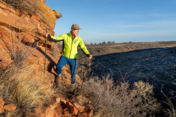 senior male hiker with trekking poles at sandstone cliff in Lory State Park in COlorado foothills