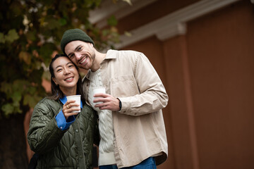 Obraz premium Smiling multicultural couple enjoying coffee outdoors together