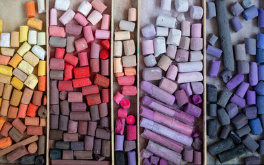 Colored soft pastels crayons in wooden case. Painter's multicolor background. Chalk pieces top view