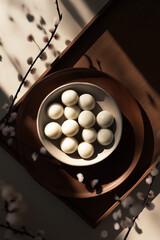 White eggs arranged in a round ceramic bowl on a wooden tray, surrounded by delicate branches, creating a serene and minimalist aesthetic with natural light