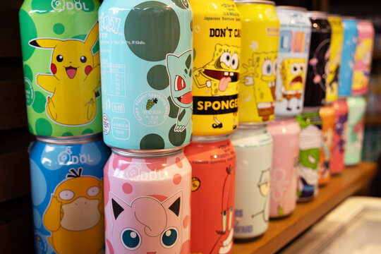 Several beverage cans with colorful and animated prints featuring characters like Pikachu and SpongeBob SquarePants; part of the image is blurred.