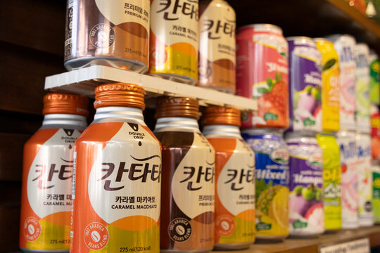 A shelf displays various beverages, including small bottles with labels written in Chinese, and to the right of the image, out-of-focus colorful cans