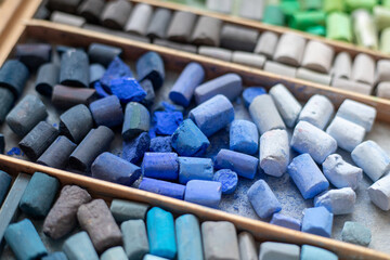 Blue gray soft pastels crayons collection in wooden case. Painter's multicolor background. Chalk pieces top view