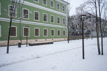 Cluj-Napoca/Romania. 1/07/2026: Snow covered pedestrian area next to historic green building in winter