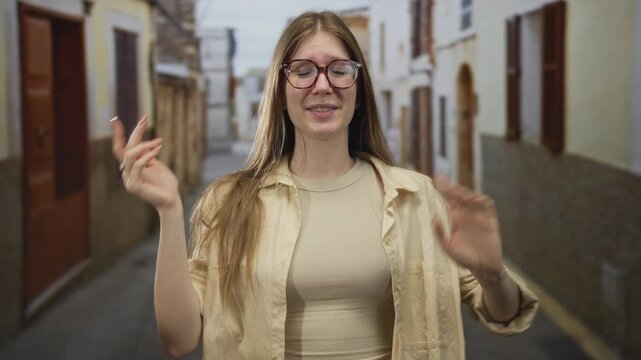 Woman wearing glasses and a beige shirt holds out hands with a puzzled expression on a street; uncertainty.