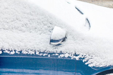 Car partially covered in snow revealing side mirror in winter conditions
